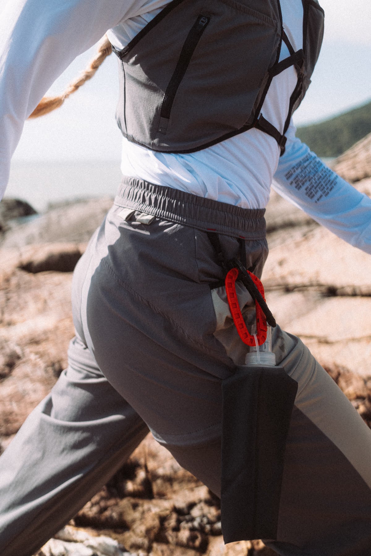 Detalhe da calça com mosquetão vermelho e garrafa na lateral