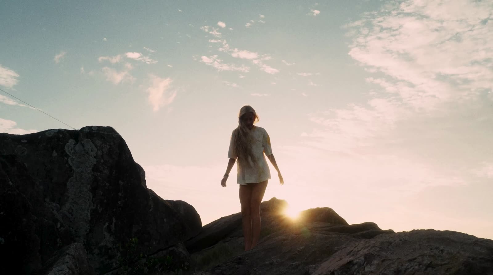 Silhueta de mulher sobre a pedra com o sol nascendo